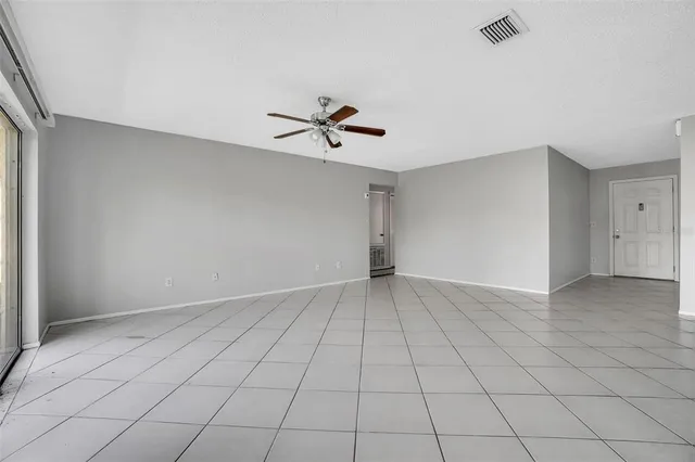an empty room with windows and ceiling fan
