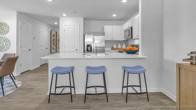 a kitchen with stainless steel appliances kitchen island granite countertop a dining table chairs and a refrigerator