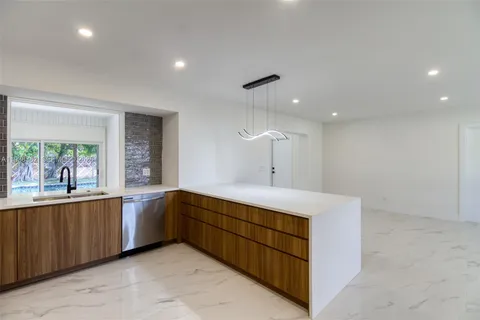 a large kitchen with stainless steel appliances a large counter top a sink a stove and a window