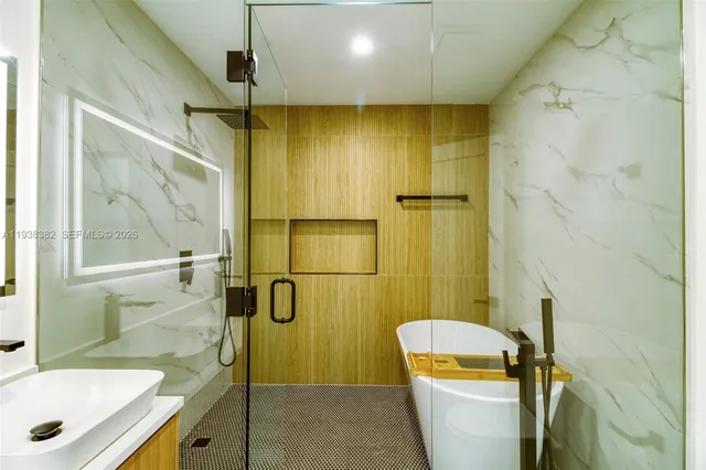 a bathroom with a tub a sink a mirror and shower