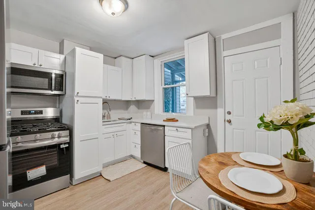 a kitchen with stainless steel appliances a white table and chairs in it