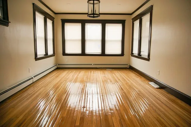a view of empty room with wooden floor and fan