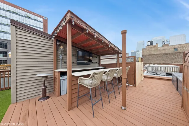 a view of a roof deck with table and chairs a barbeque with wooden floor and floor to ceiling window