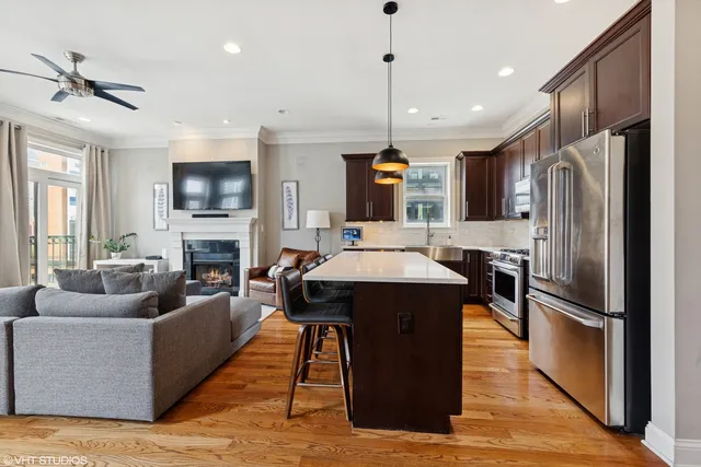 a kitchen with stainless steel appliances granite countertop a refrigerator a oven a sink a stove and a dining table with wooden floor