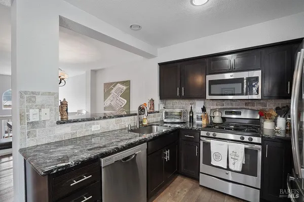 a kitchen with stainless steel appliances granite countertop a stove microwave and sink