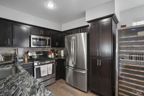 a kitchen with stainless steel appliances granite countertop a refrigerator a stove and a sink with wooden floor