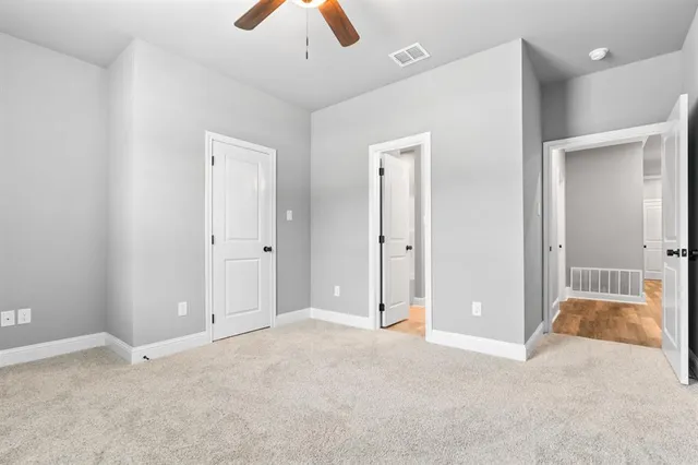 an empty room with closet and a chandelier fan
