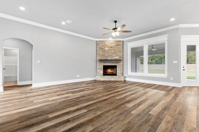 a view of an empty room with wooden floor fireplace and a window