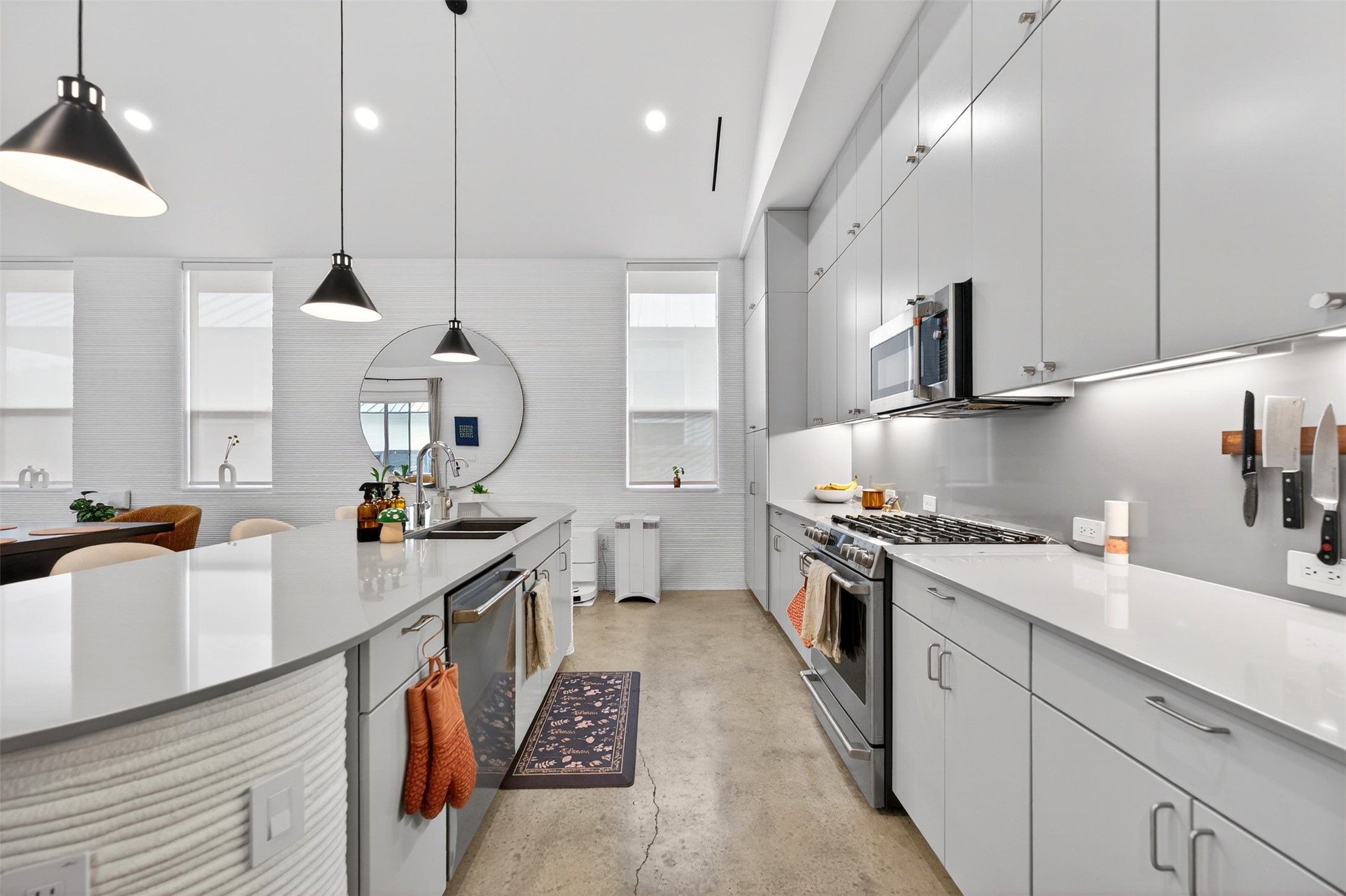 308 Painted Sunset Drive Georgetown, TX 78628 - Photo 11 of 26 Modern kitchen featuring a large island with an integrated sink, stainless steel appliances, extensive cabinetry, light-toned countertops, and concrete-finish flooring