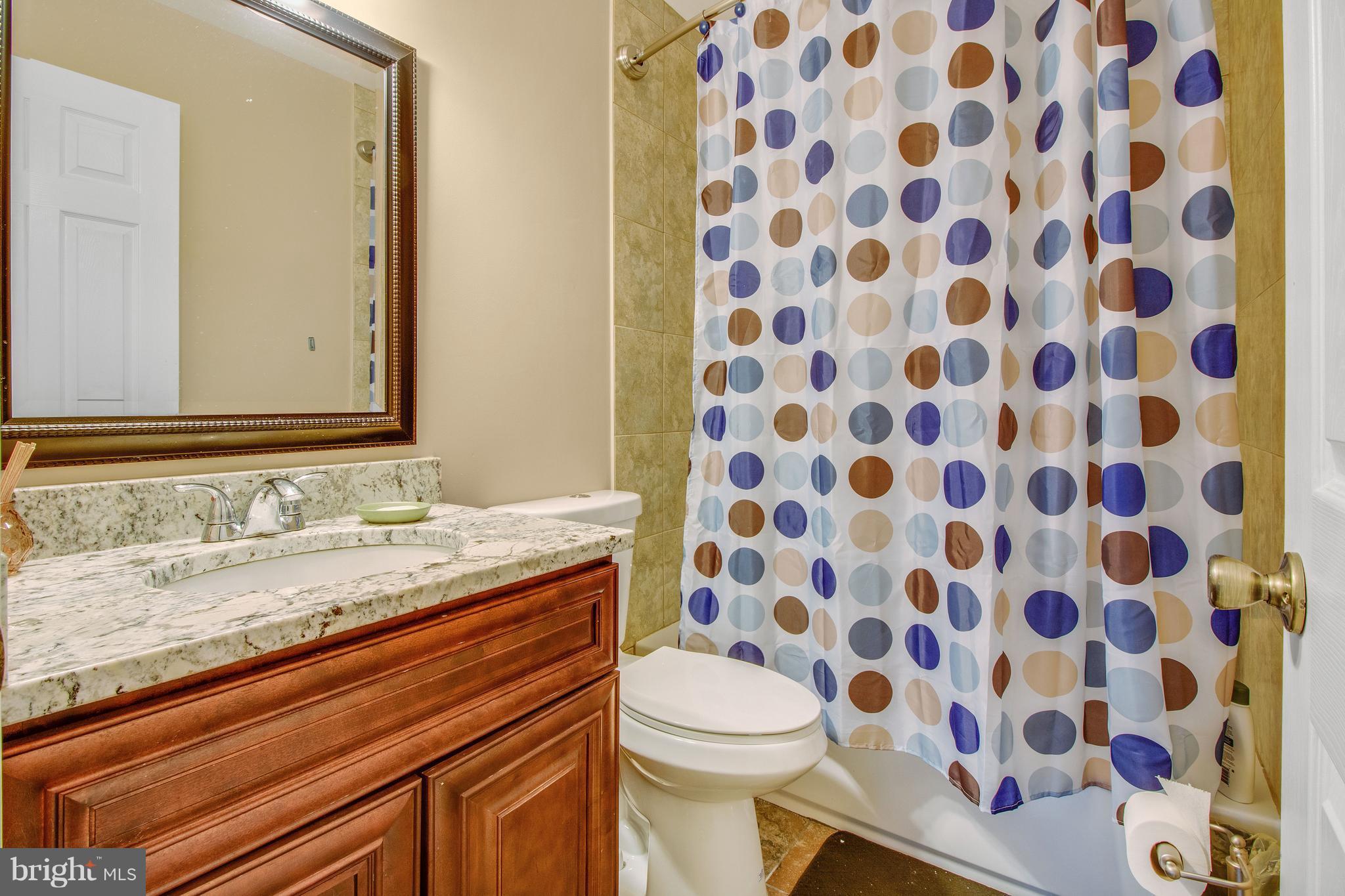 3708 Collier Road Randallstown, MD 21133 - Photo 11 of 25 a bathroom with a granite countertop toilet a sink and a mirror