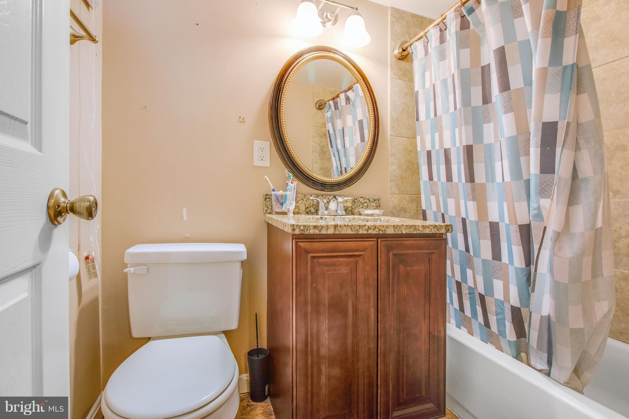 3708 Collier Road Randallstown, MD 21133 - Photo 21 of 25 a bathroom with a toilet a sink and a mirror