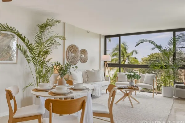 a view of a dining room with furniture one side kitchen view and wooden floor