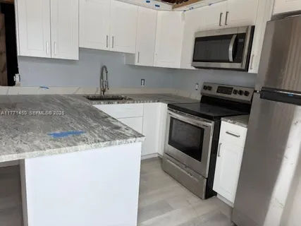 a kitchen with granite countertop a sink stove and microwave