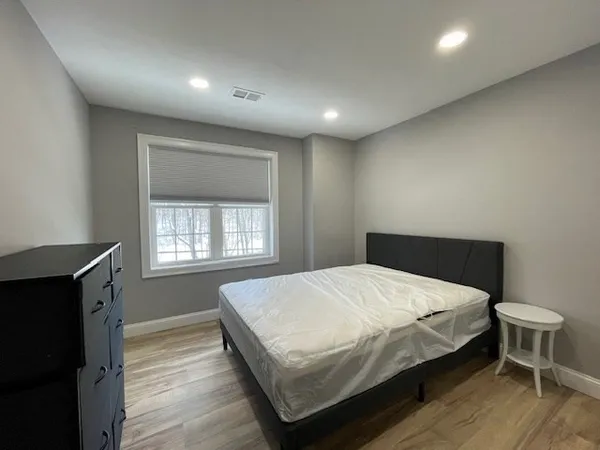 a large bedroom with a bed and wooden floor
