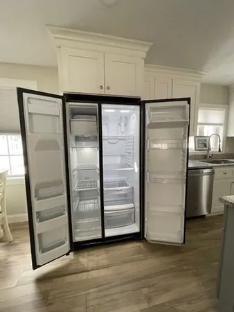 a view of a refrigerator in kitchen and an empty room