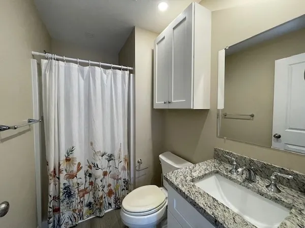 a bathroom with a granite countertop sink mirror vanity and toilet