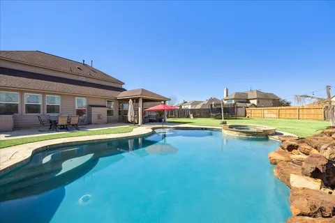 a view of a swimming pool with a lawn chairs and floor to ceiling window