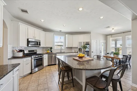 a kitchen with granite countertop kitchen island white cabinets and stainless steel appliances