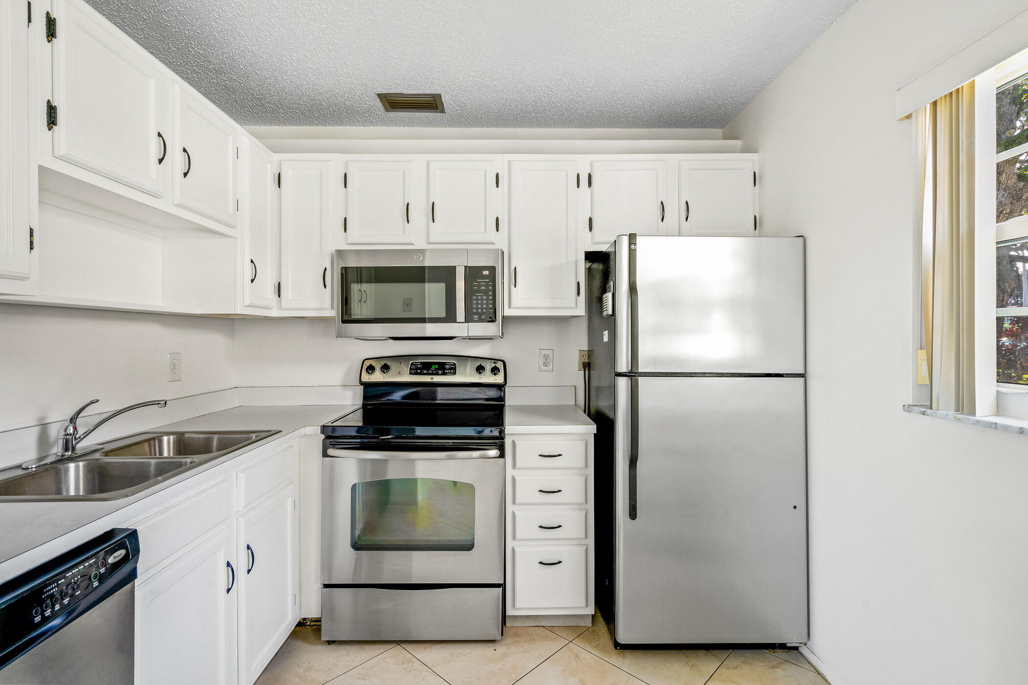 Undisclosed Address Vero Beach, FL 32962 - Photo 6 of 34 a kitchen with white cabinets and stainless steel appliances