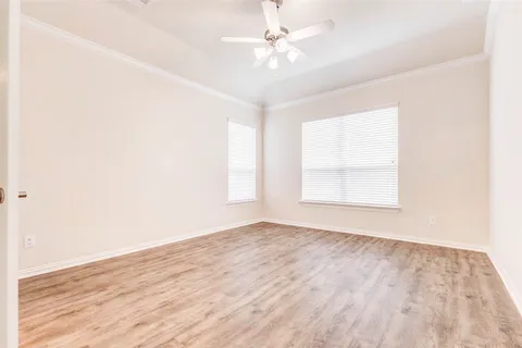 an empty room with wooden floor fan and windows