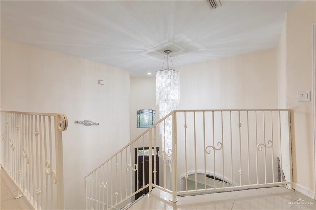 2001 Quail Lane Mission, TX 78572 - Photo 12 of 28 Staircase featuring decorative wrought iron railings and a multi-tiered pendant light fixture