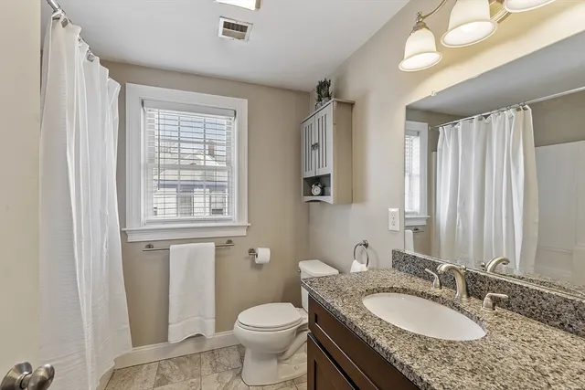 a bathroom with a granite countertop sink toilet and mirror