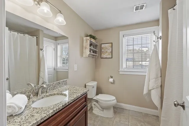 a bathroom with a granite countertop sink a mirror and a toilet