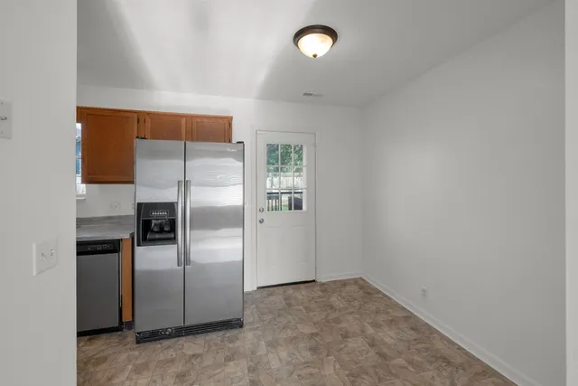 a view of a refrigerator in kitchen and an empty room