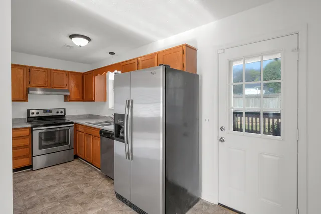 a kitchen with granite countertop a refrigerator and a stove top oven