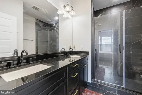 a bathroom with a granite countertop sink a large mirror and a shower