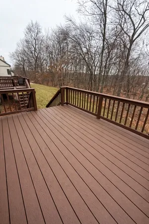 a view of deck with wooden floor and trees in the back