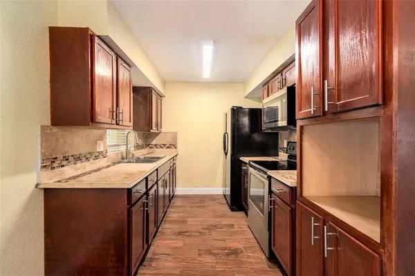 a kitchen with stainless steel appliances granite countertop a refrigerator a stove and a sink