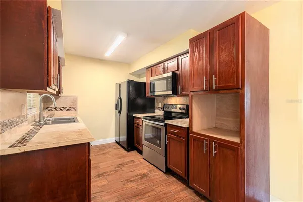a kitchen with kitchen island granite countertop wooden cabinets stainless steel appliances and a sink