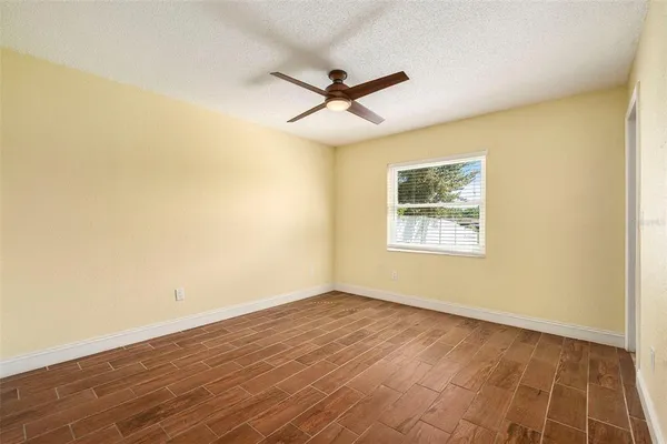 an empty room with a window and ceiling fan