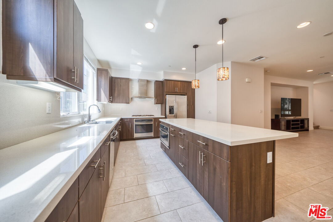 a large kitchen with kitchen island a sink a counter top stainless steel appliances and cabinets