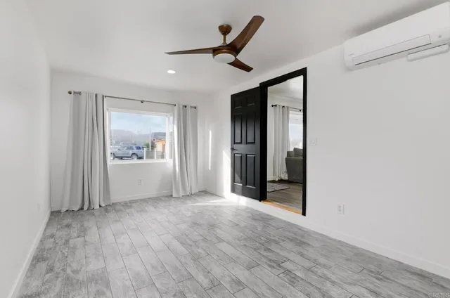 a view of a hallway to a livingroom with wooden floor and a ceiling fan