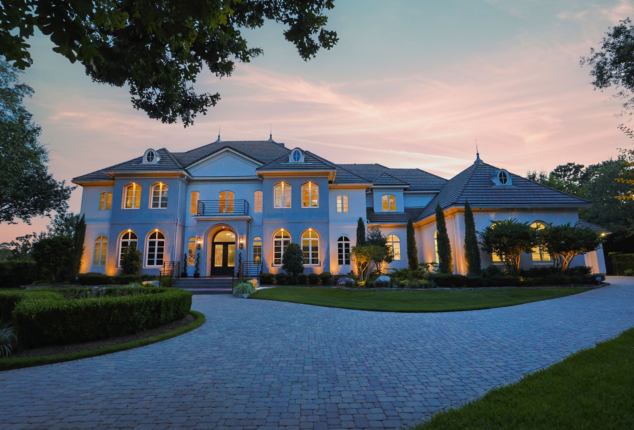 39 Maymont Way Spring, TX 77382 - Photo 2 of 50 This stunning two-story home features elegant architecture with a grand entrance, large windows, and a beautifully landscaped driveway, set against a picturesque sunset backdrop.