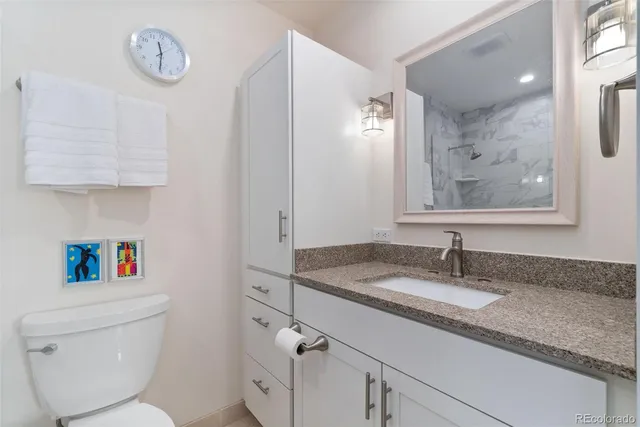 a bathroom with a granite countertop sink a toilet and a mirror