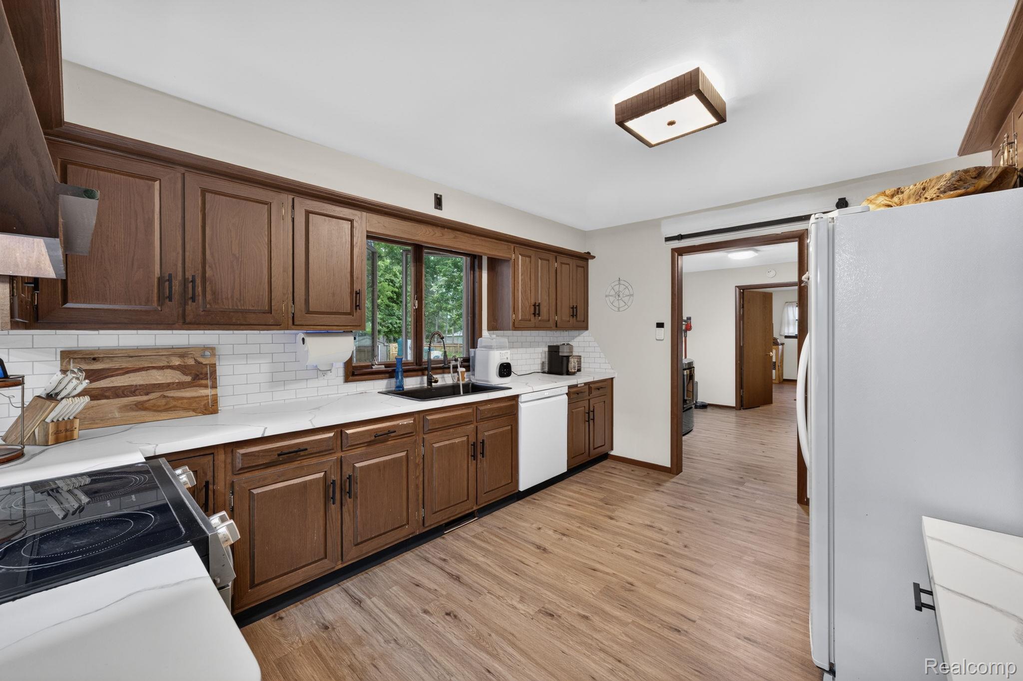 5330 Sheridan Road Saginaw, MI 48601 - Photo 21 of 50 Kitchen featuring wood-finish cabinetry, white countertops, a white subway tile backsplash, and wood-finish flooring