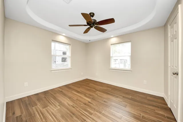 a view of empty room with wooden floor and ceiling fan