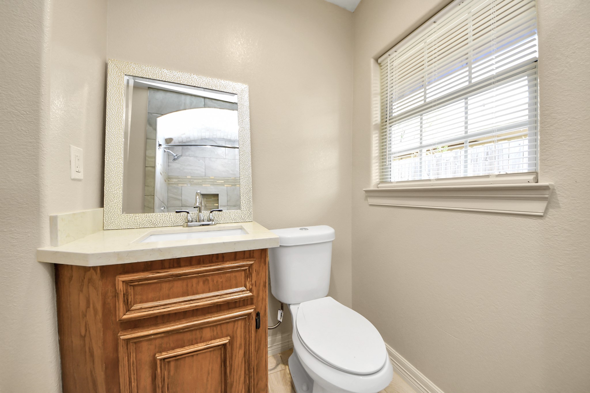 8925 Homewood Lane Houston, TX 77078 - Photo 21 of 28 a bathroom with a granite countertop toilet a sink a mirror and a window