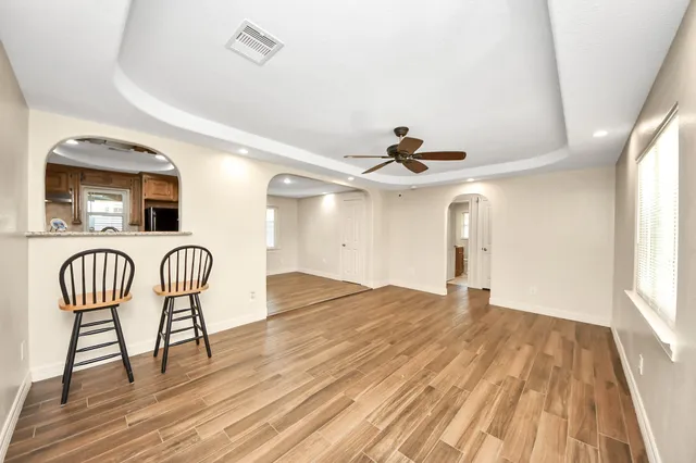 a view of a livingroom with furniture wooden floor ceiling fan and windows