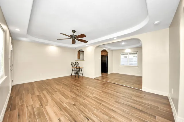 a view of empty room with wooden floor and fan