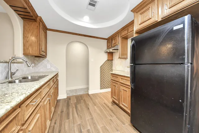 a kitchen with granite countertop a refrigerator a sink and dishwasher