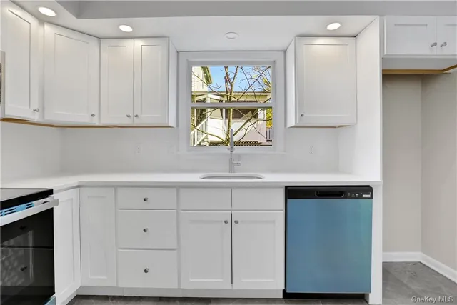 a kitchen with white cabinets and window