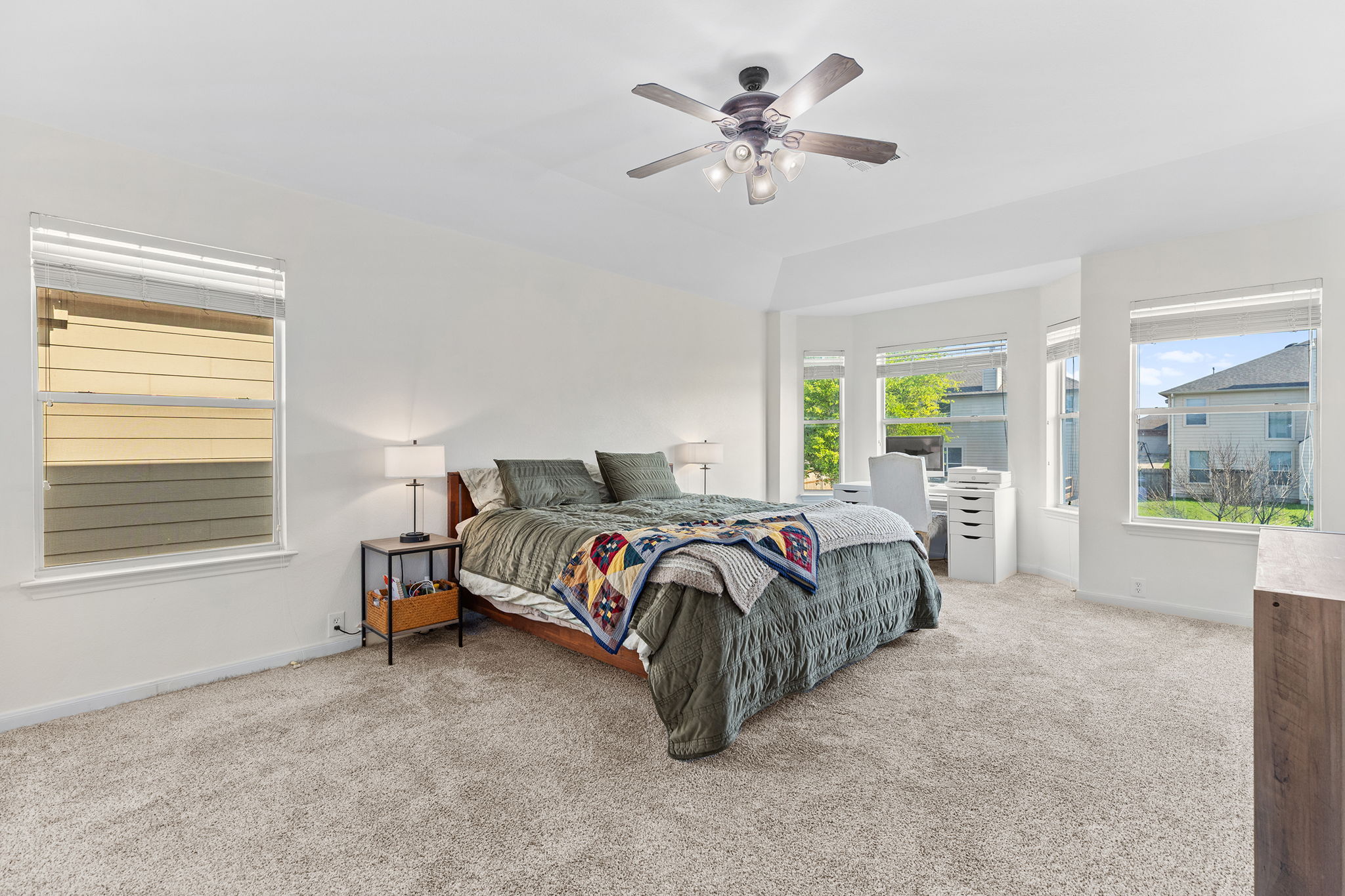 3517 Shiraz Loop Round Rock, TX 78665 - Photo 5 of 40 Spacious bedroom featuring light-toned carpeting, a ceiling fan with integrated lighting, multiple windows with blinds, and a prominent bay window area
