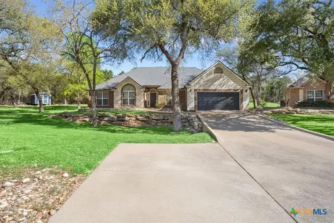 a front view of a house with a garden and trees