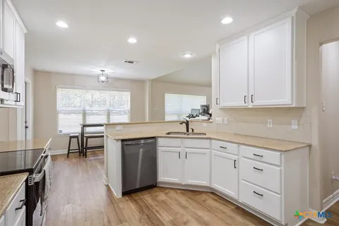 a kitchen with white cabinets and sink