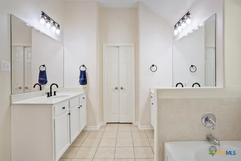 a spacious bathroom with a tub sink and mirror