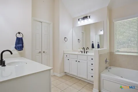 a bathroom with a double vanity sink mirror and bathtub